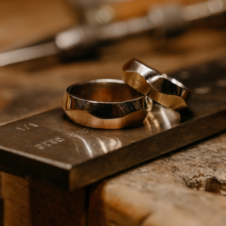 Artisan two-tone wedding bands on metal jeweler's block.