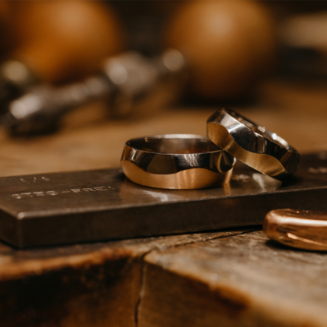 Two-tone wedding rings on rustic woodworking bench.
