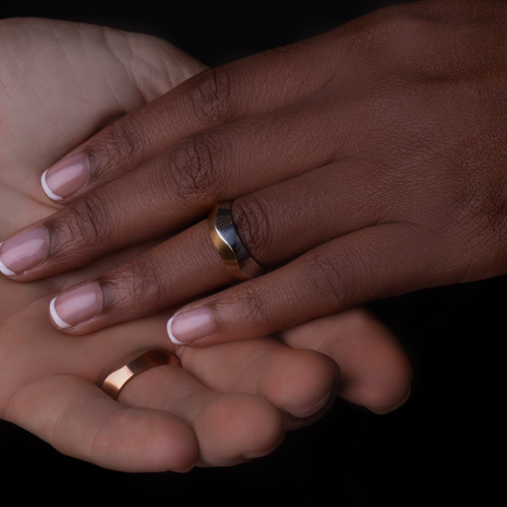 Interlocked hands showing simple gold wedding rings.