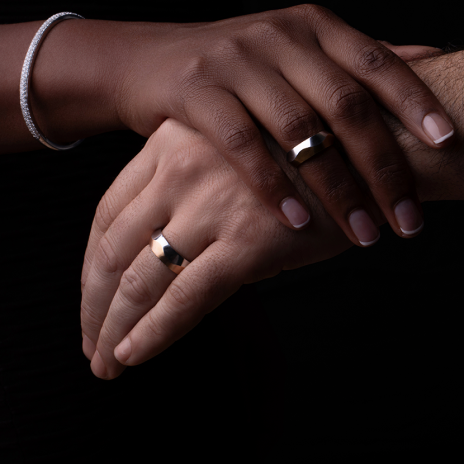 Couple’s hands with matching gold wedding bands.