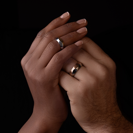 Couple clasping hands with silver wedding bands.