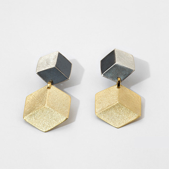 Two  earrings featuring 2 hexagon shapes in a row, reminiscent of 3D cubes, the top one sterling silver and the bottom one gold-plated.