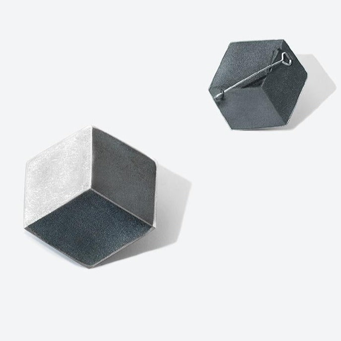 Seen from the front and back: a hexagon shaped brooch, reminiscent of a 3D cube, in sterling silver.
