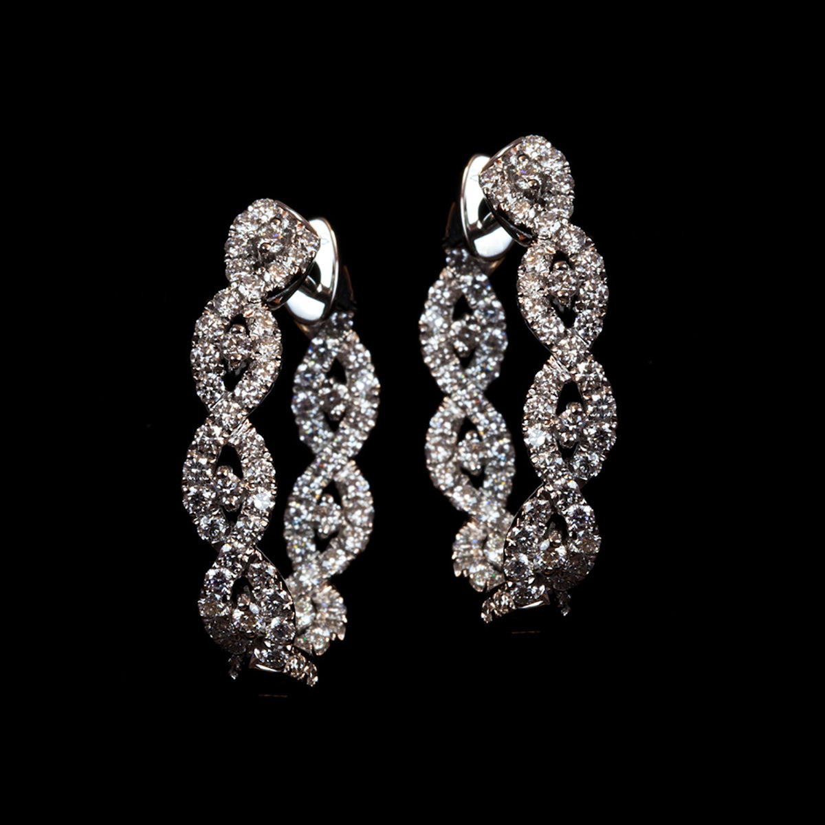 Diamond Intertwined White Gold Small Hoop Earrings on a black background